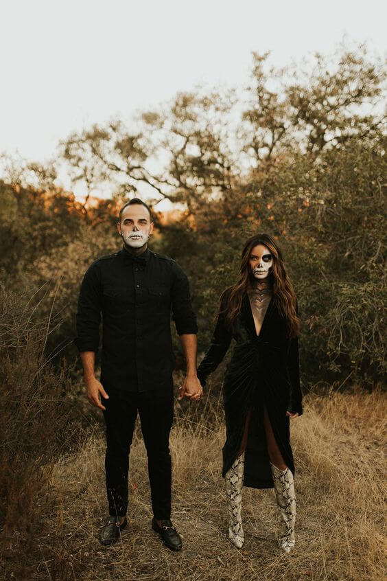 A couple wearing Halloween masks in a forest during rains.